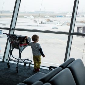 little-boy-standing-at-window-in-airport-and-P3XTQML